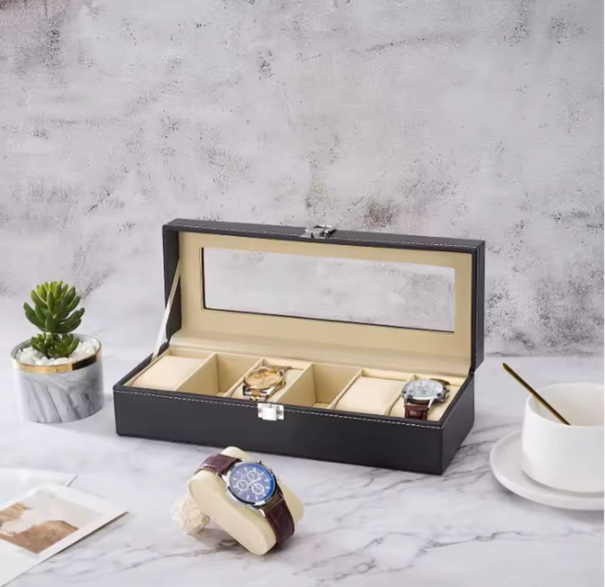 Caja para 6 relojes tipo cuero negro con tapa transparente sobre mesa
